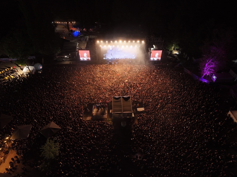 Tłum publiczności przed oświetloną sceną Progresji podczas koncertu o zmierzchu w Warszawie