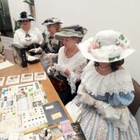 Kobiety w strojach historycznych z przełomu XIX i XX wieku grają w gry planszowe podczas wydarzenia w Archiwum Państwowym w Przemyślu