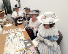 Kobiety w strojach historycznych z przełomu XIX i XX wieku grają w gry planszowe podczas wydarzenia w Archiwum Państwowym w Przemyślu
