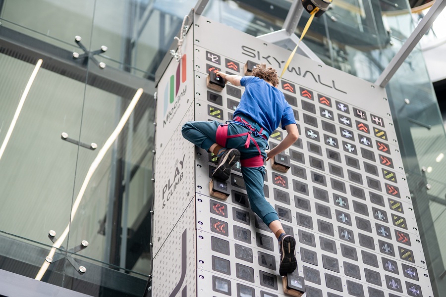 Uczestnik wspinający się na interaktywnej ściance SkyWall w Galerii Młociny
