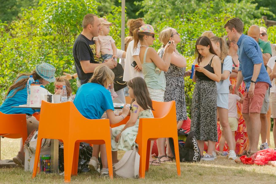 Dzieci i rodzice podczas warsztatów kreatywnych na Warszawskim Kocykowaniu - malowanie twarzy w plenerze w warszawskim parku