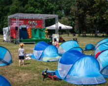 Dzieci oglądające interaktywny spektakl teatralny na scenie Warszawskiego Kocykowania w parku - namioty pop-up na trawie przed sceną