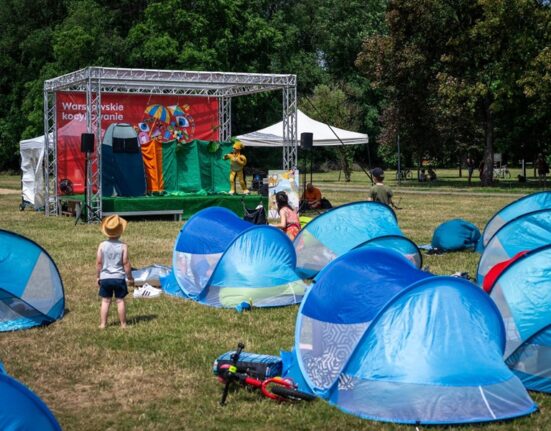 Dzieci oglądające interaktywny spektakl teatralny na scenie Warszawskiego Kocykowania w parku - namioty pop-up na trawie przed sceną